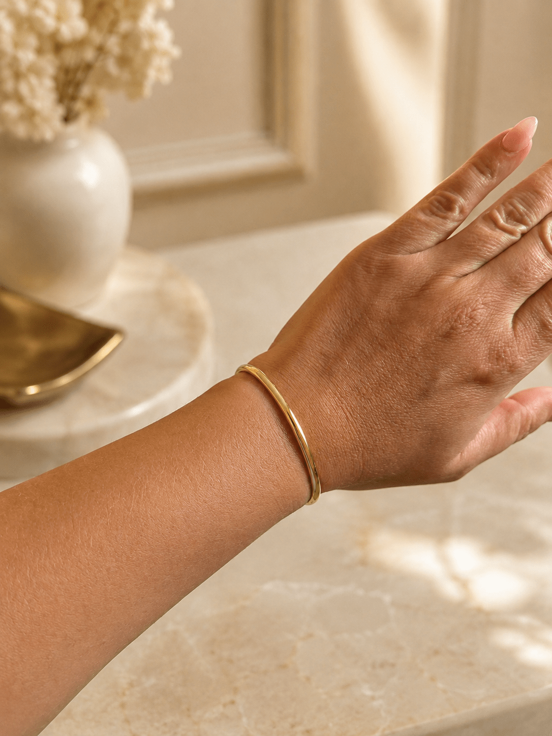 18k apzeltīta minimālistiska bangle rokassprādze uz gaiša fona